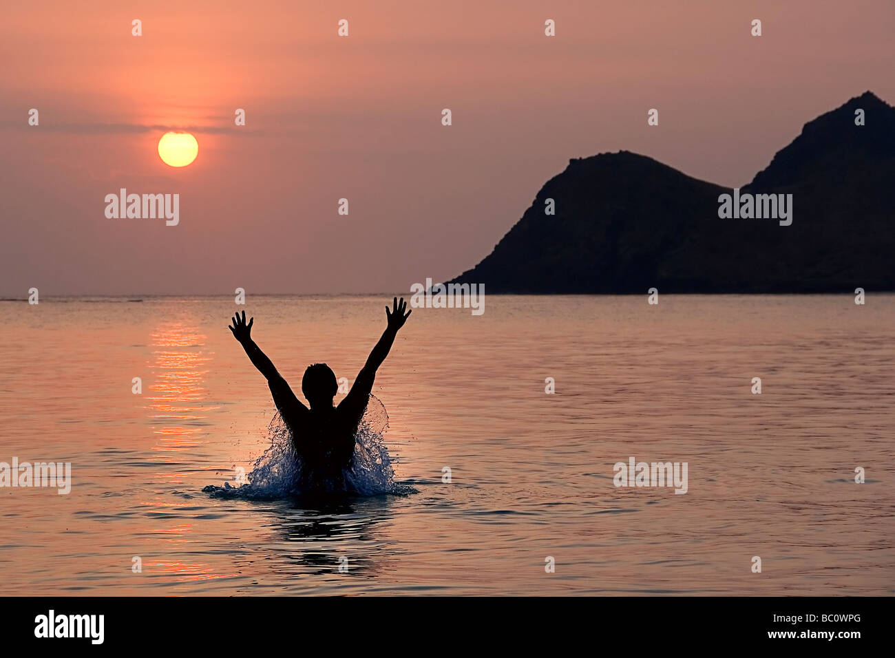 Person jumps up in ecstasy with the rising sun. The morning sun is a fireball from the volcanic fog VOG. Stock Photo