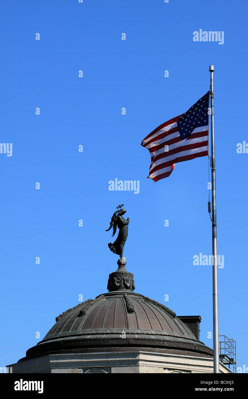 Bronze angel atop the Sacristy at the Cathedral of St. Paul, Minnesota prays to a U.S. flag flying nearby Stock Photo