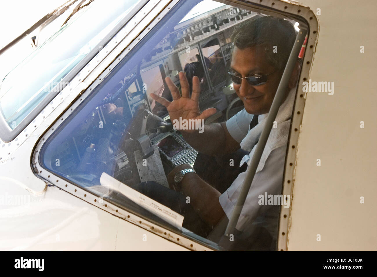 Airline pilot waving to passengers boarding plane Stock Photo