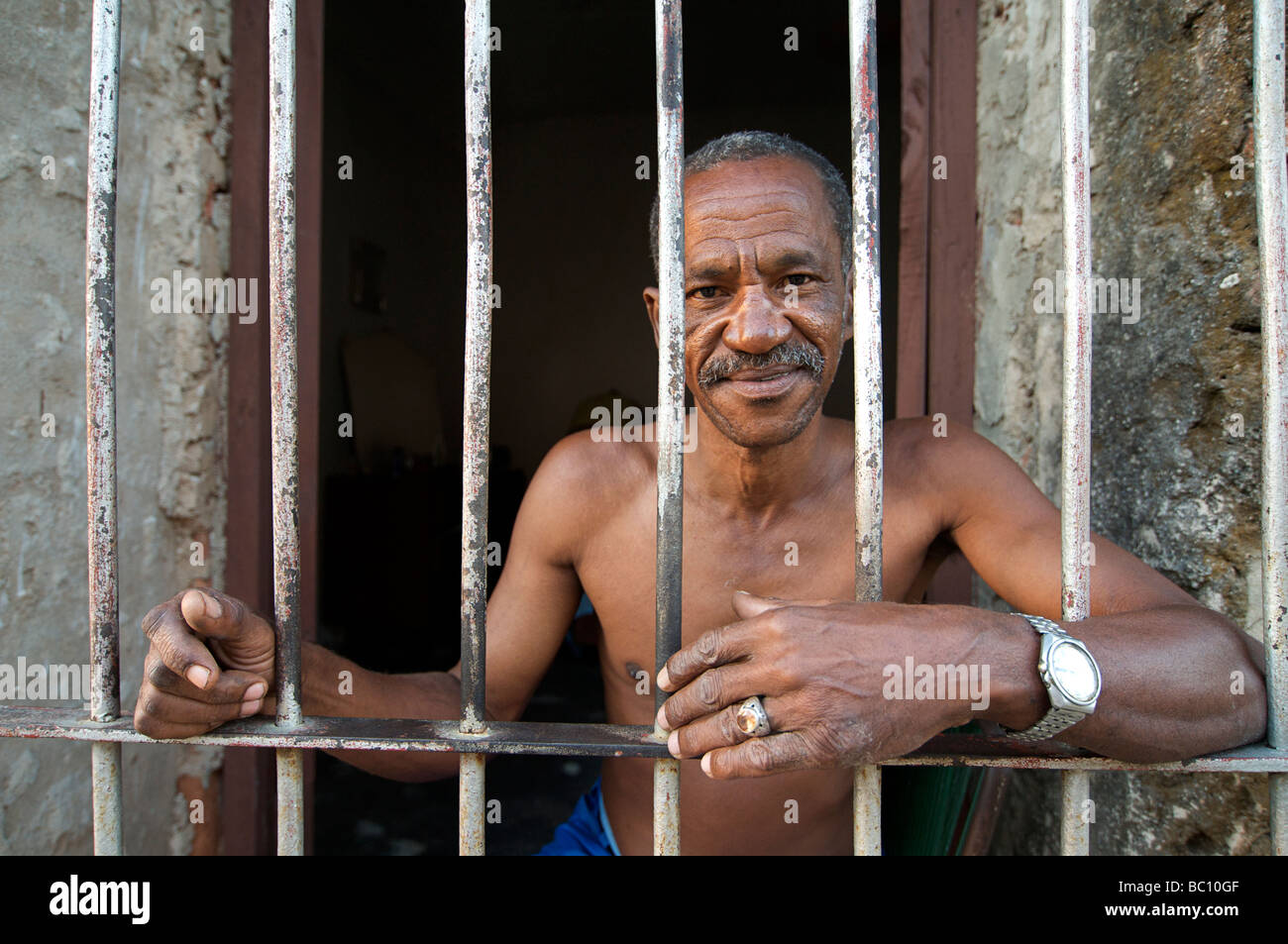 Friendly Cuban man sitting in the doorway of his  home, Trinnidad, CUBA. MODEL RELEASED SUBJECT Stock Photo