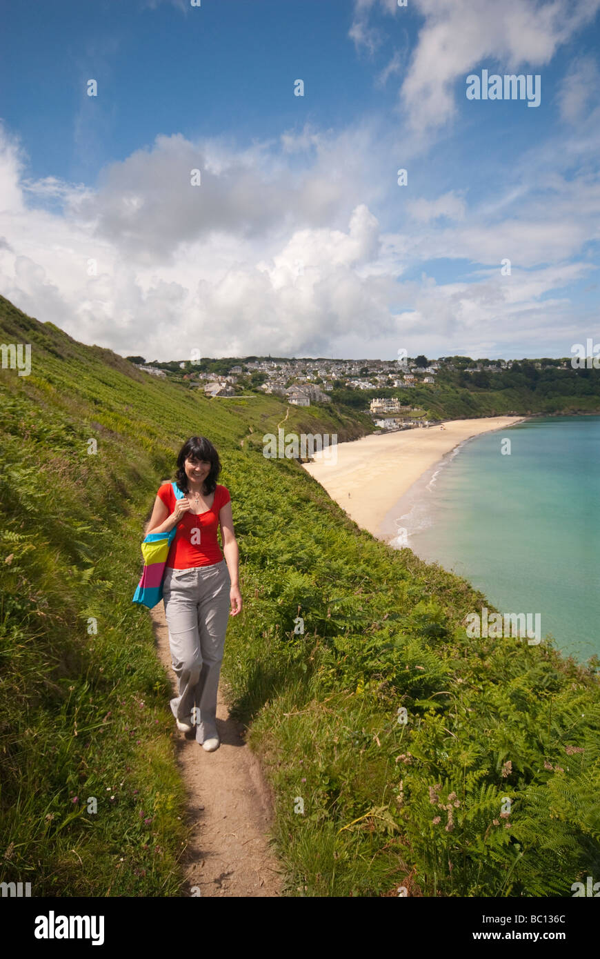 Woman walking along the coastal path close to Carbis Bay in Cornwall in Summer Stock Photo