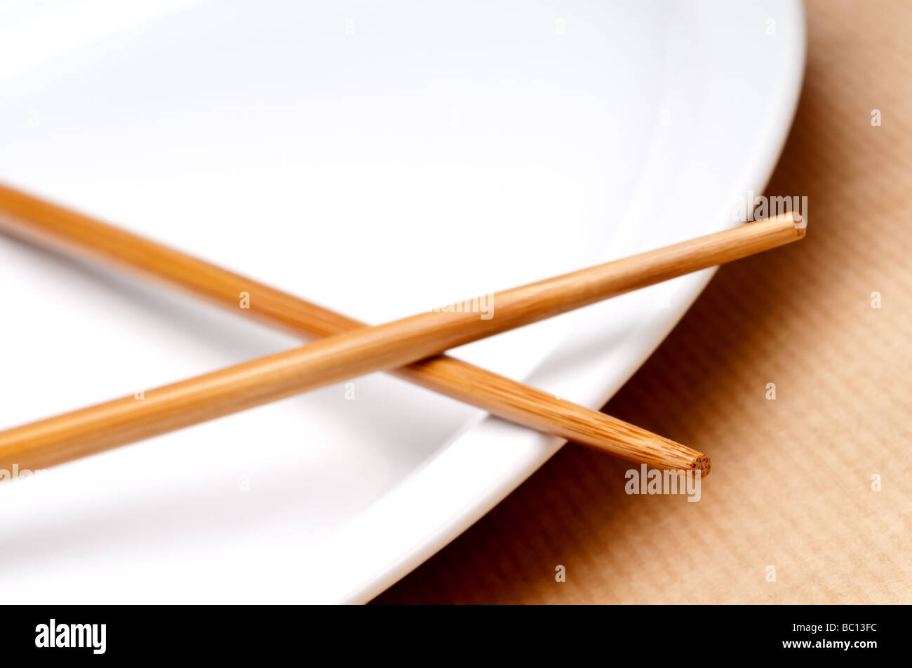 a tilted horizontal macro of a pair of chopsticks on a white plate Stock Photo
