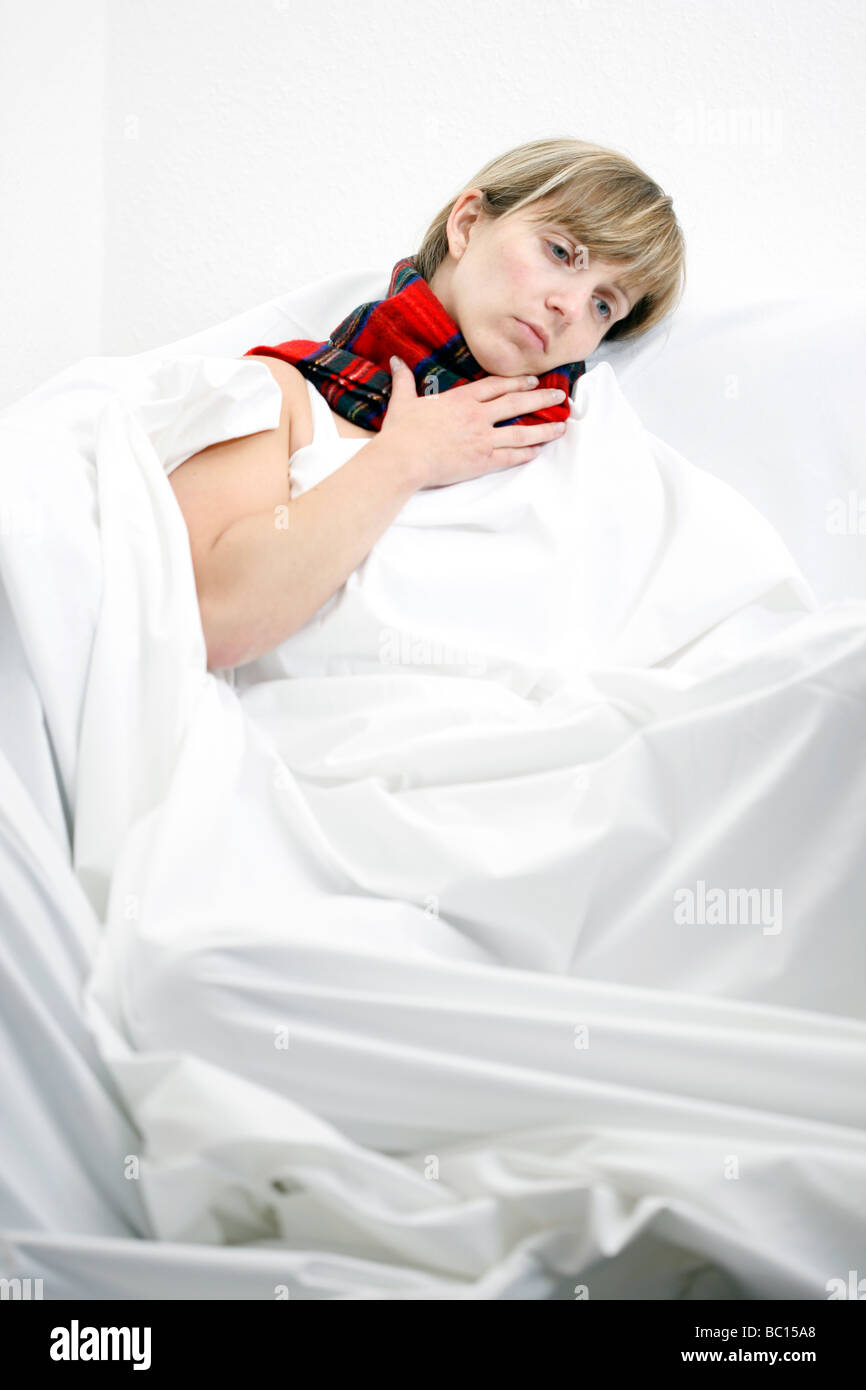 Woman with a scarf in bed has a cold a sore throat Stock Photo Alamy