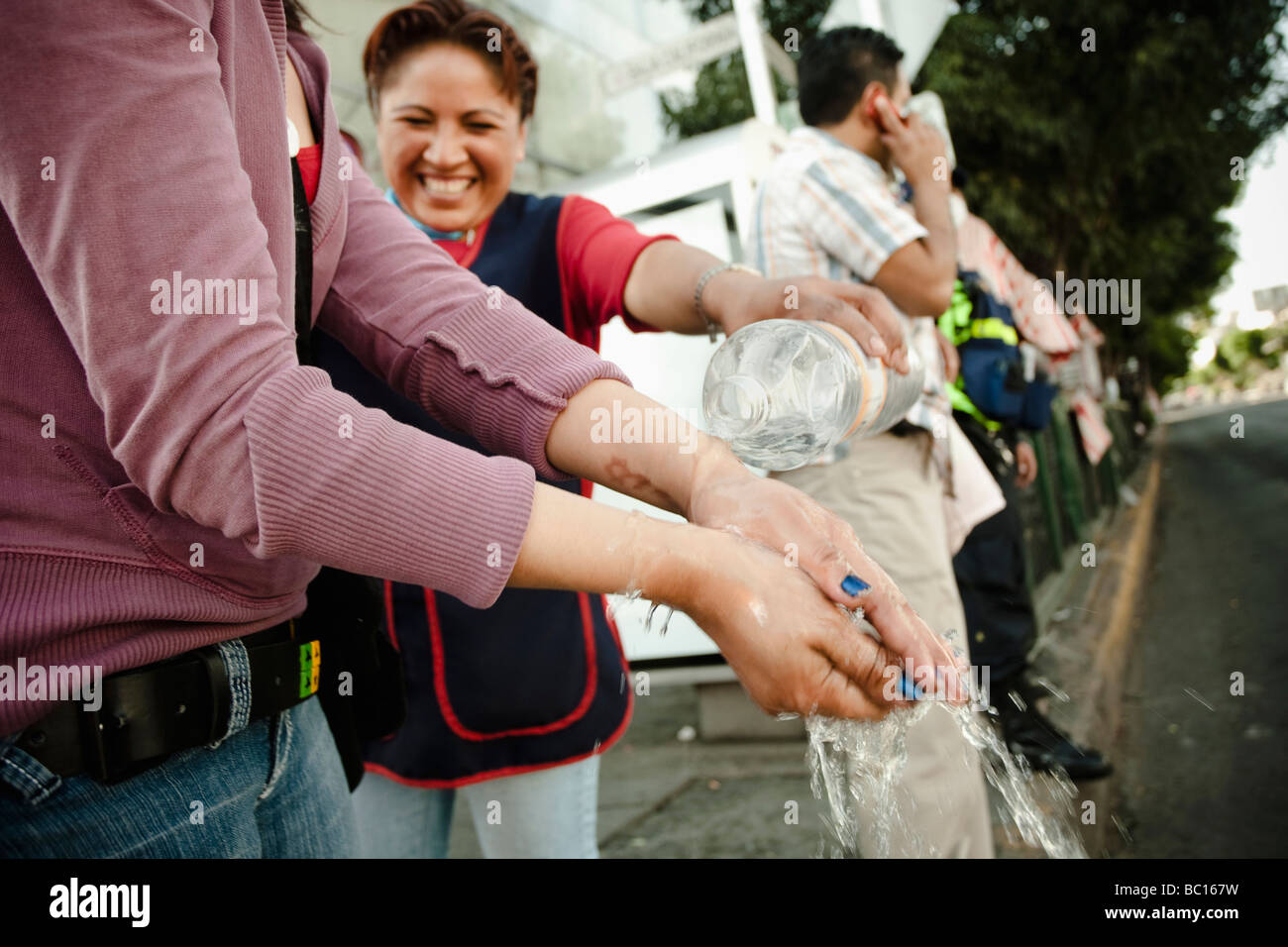 A woman cleans other's hands with a bottle of water during the swine flu epidemic in Mexico City, DF, Mexico. Stock Photo