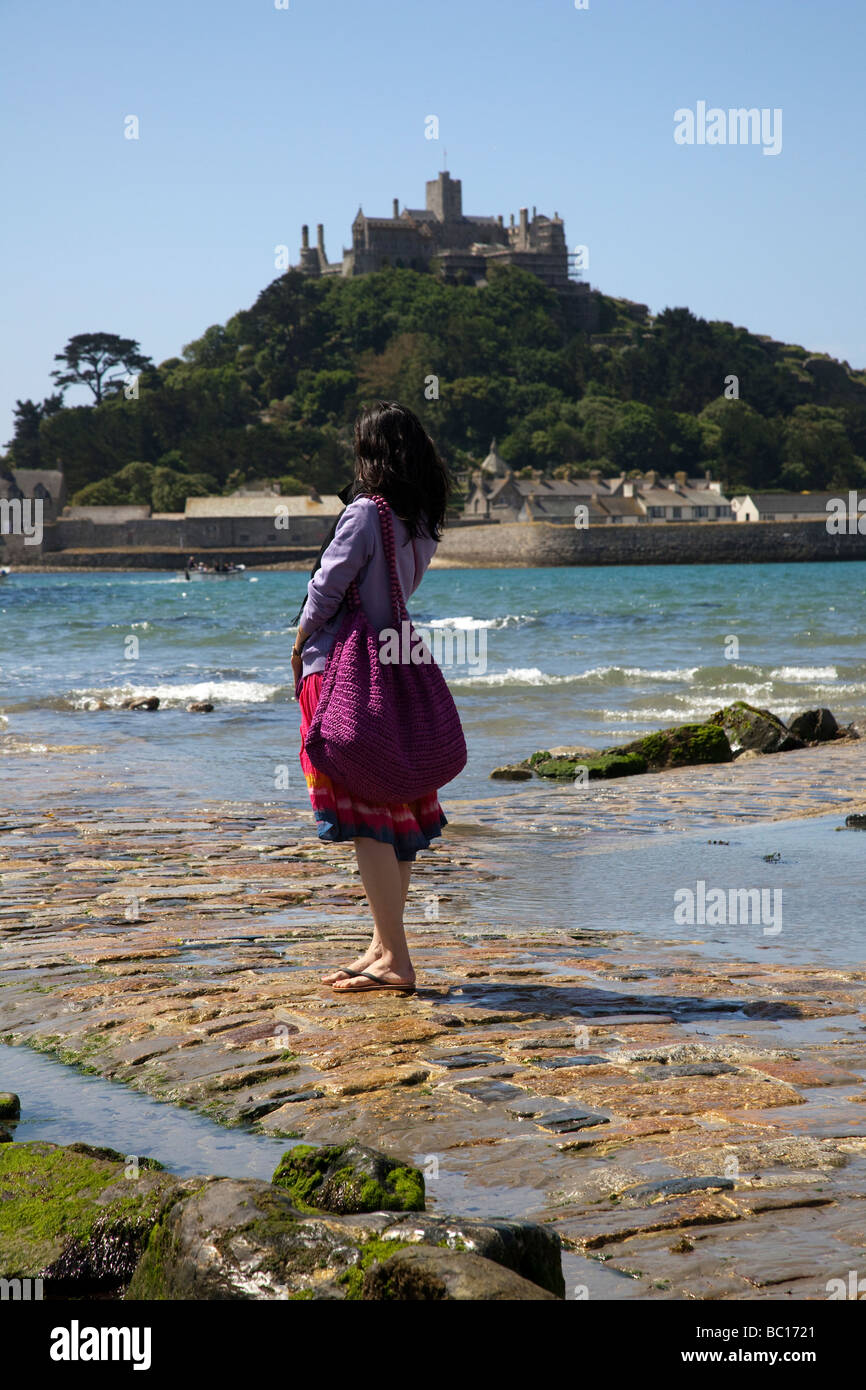 Portrait of a Chinese female Tourist crossing the tidal Causeway at St Michaels Mount, Marazion, near Penzance in Cornwall, UK Stock Photo