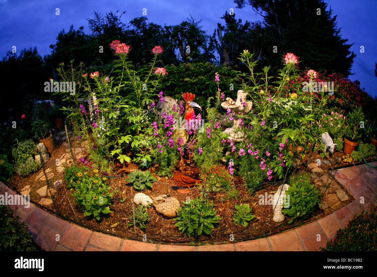 Amusing figures of a rooster, winged frog, and hippopotamus decorate a Southern California garden at twilight. Stock Photo