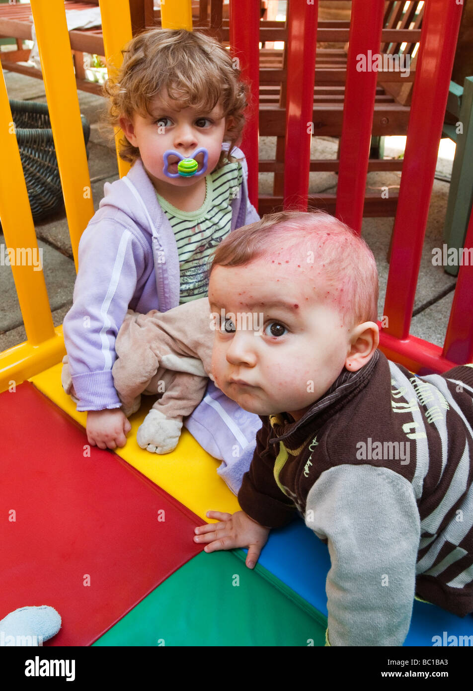 Baby with Chicken Pox in playpen with another young child. Stock Photo