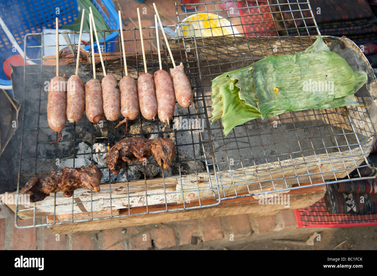 A street kitchen in Luang Prabang grilling sausages and small jungle animals Stock Photo