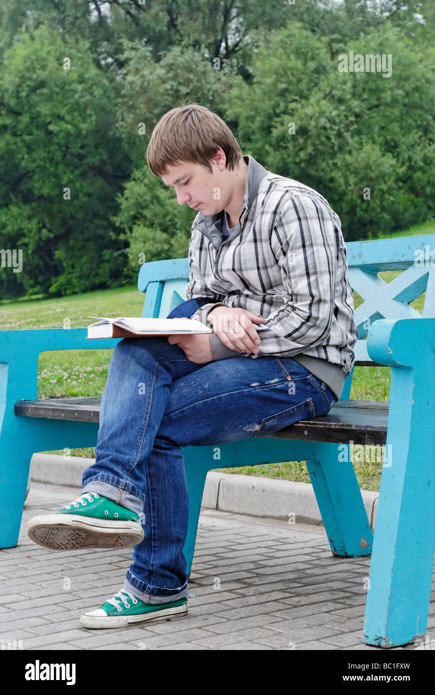Young man with book sits on the city park bench Stock Photo - Alamy