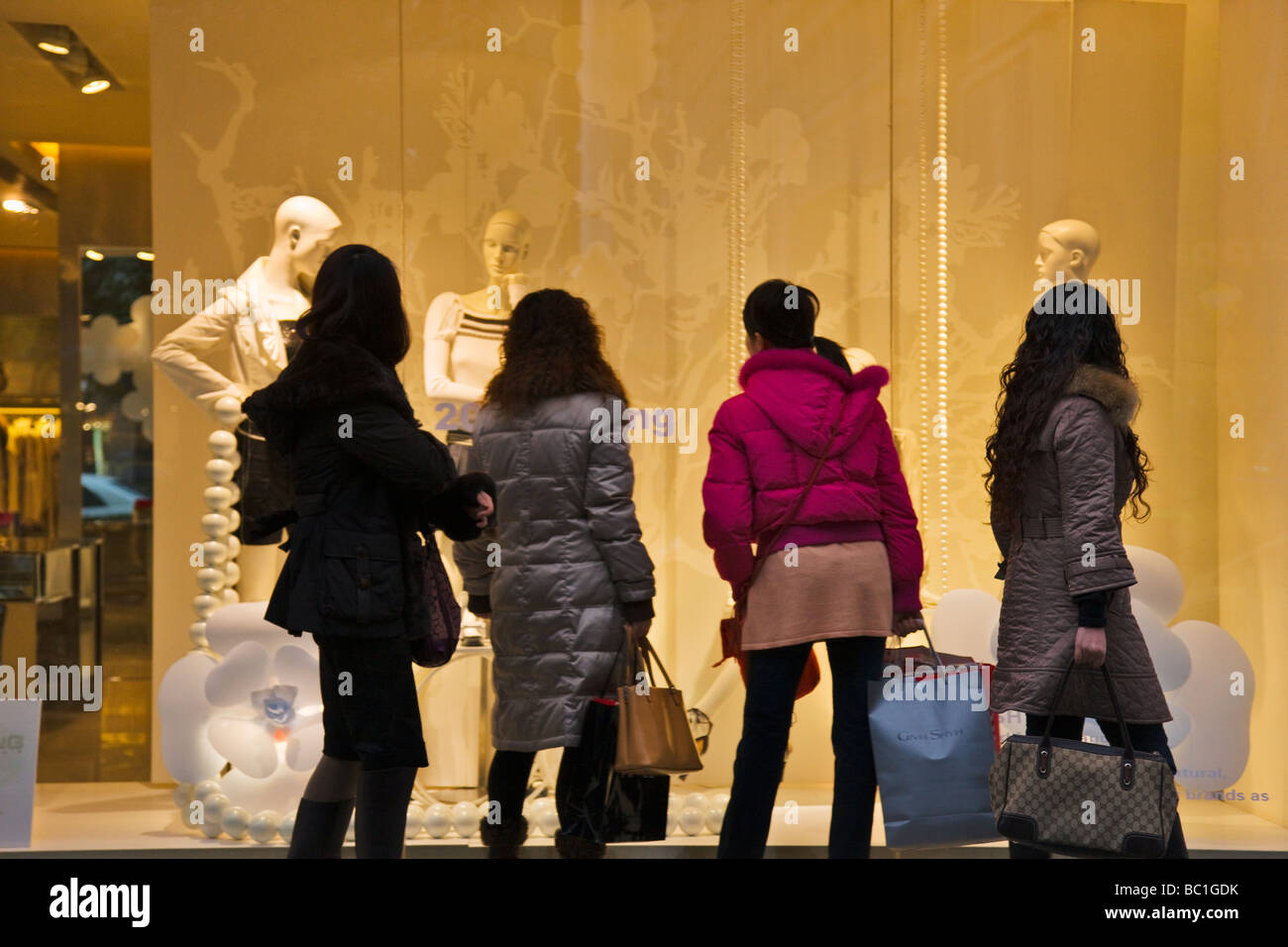 Pedestrians walk by shop window Shanghai China Stock Photo