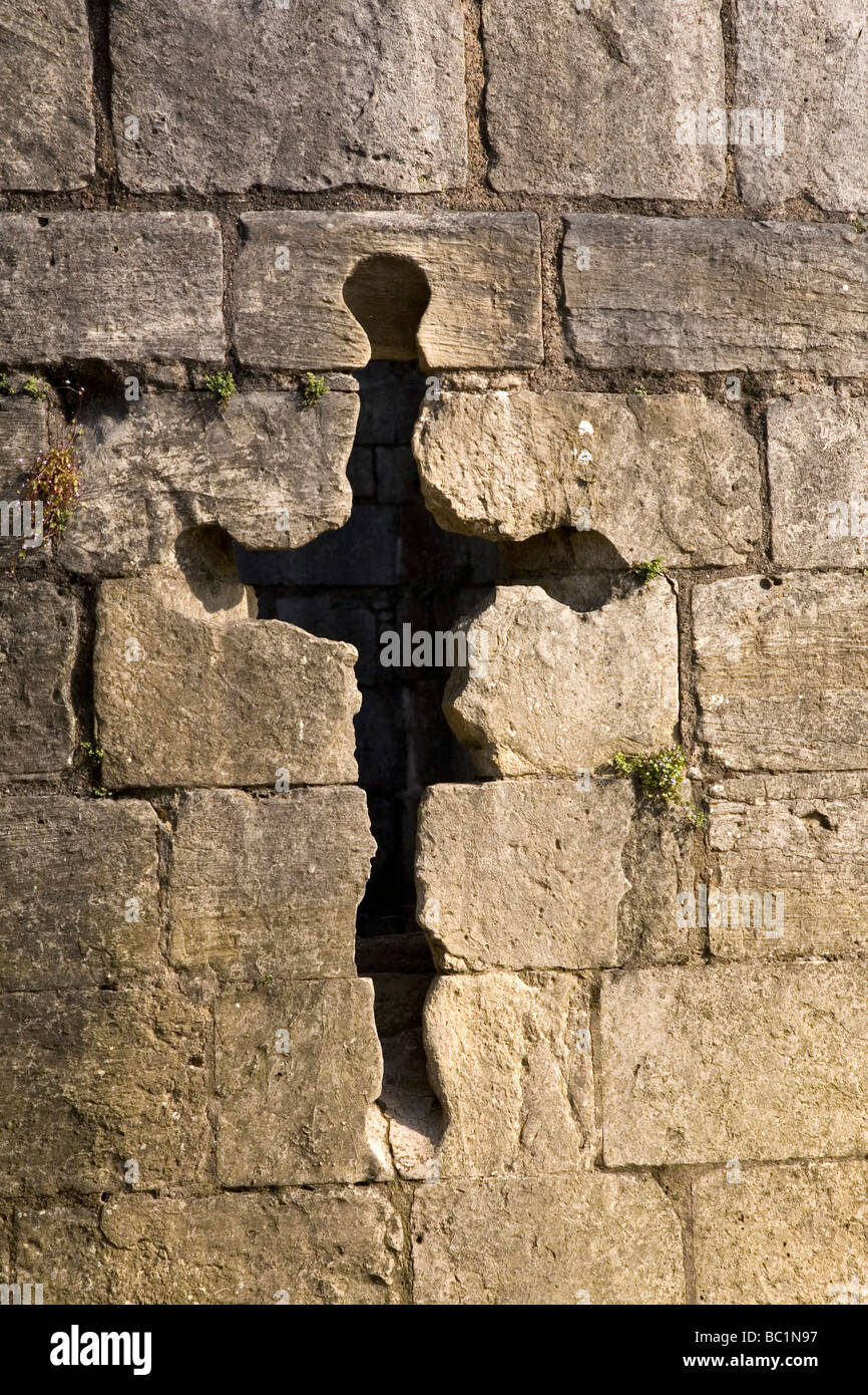 A crucifix shaped arrow slit by the river bank in the city of York, England. The tower dates from the middle ages. Stock Photo