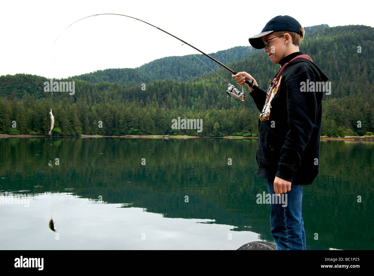 Young boy with a couple of small shiner perch wriggling in motion blur caught on a herring jig in Haida Gwaii Stock Photo