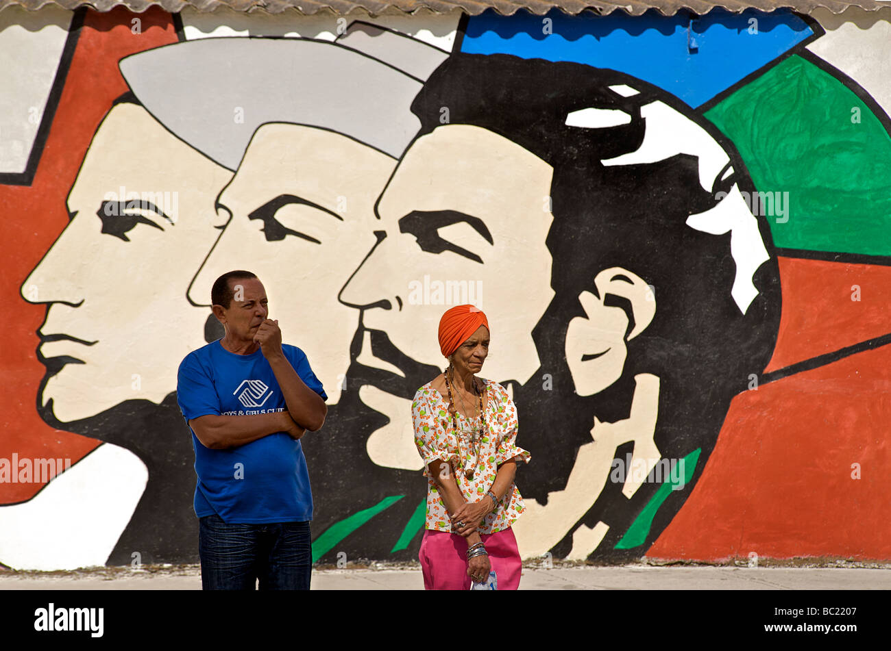 Cuban man and woman standing in front of a typical Cuban socialist wall painting. Havana, Cuba Stock Photo