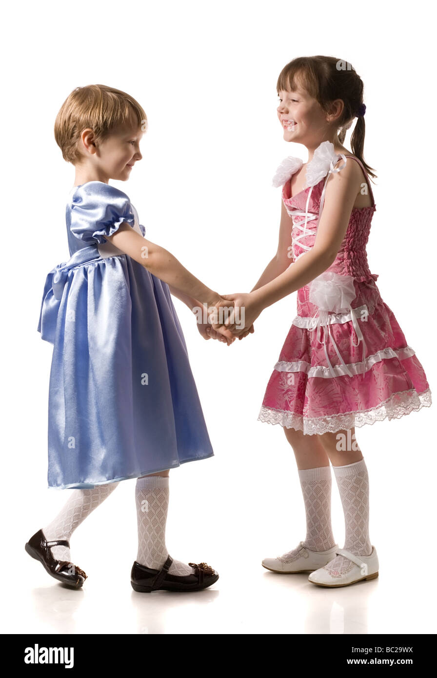 two beautiful little girls in dresses hold hands of each other and ...