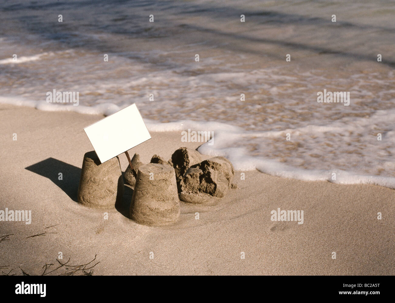 sandcastles, with a sign, breaking up on the shore Stock Photo
