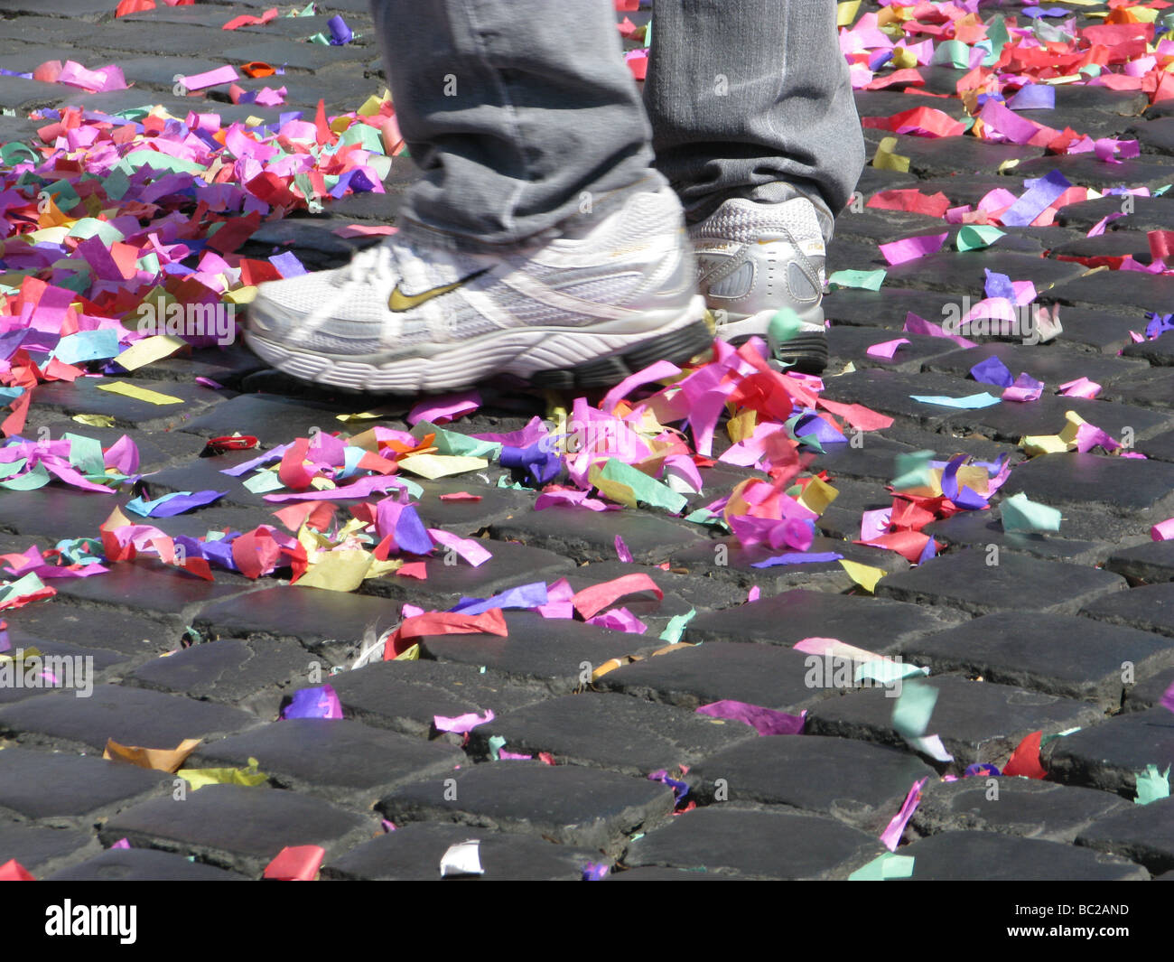 lots of colourful confetti and garlands on paved street road in sun Stock Photo