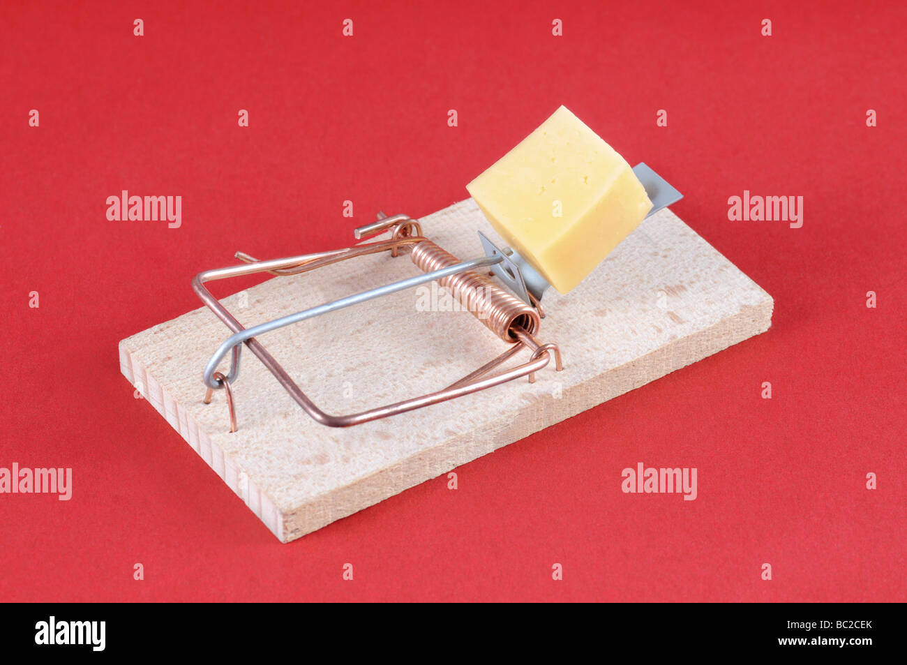 Mousetrap with a piece of cheese on red background. Stock Photo
