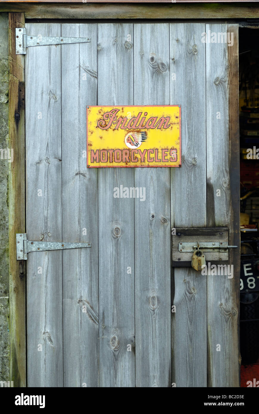 Old Indian motorcycle enamel sign on an old wooden garage door Stock Photo