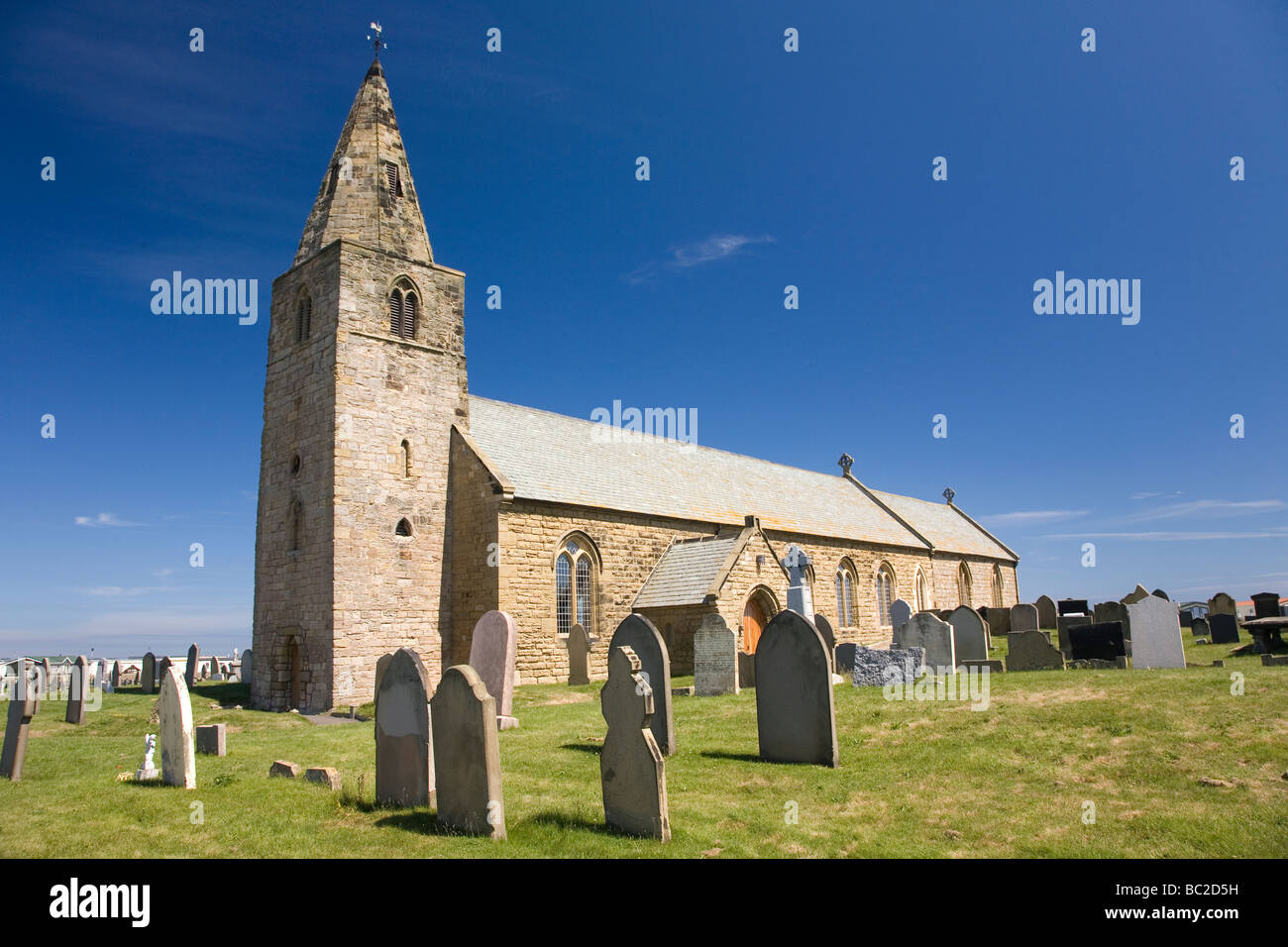St Bartholomew's Church at Newbiggin-by-the-Sea in Northumberland. Graves stand in the church yard. Stock Photo