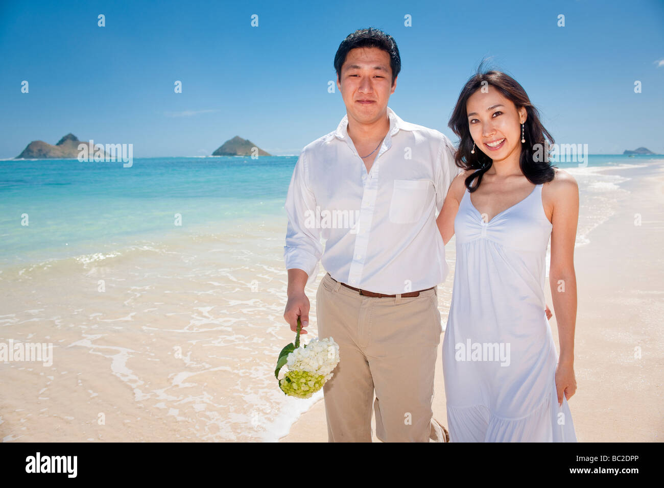 Asian Bride And Groom Stroll On Lanikai Beach As They Look Forward