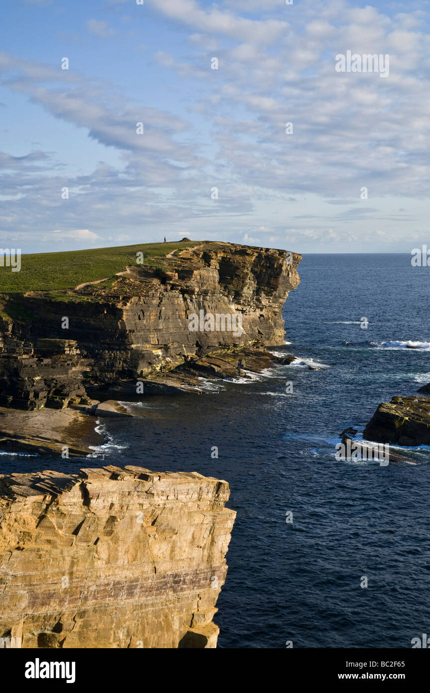 dh Brough of Bigging YESNABY ORKNEY West coast seacliff evening dusk person walking to cairn Stock Photo