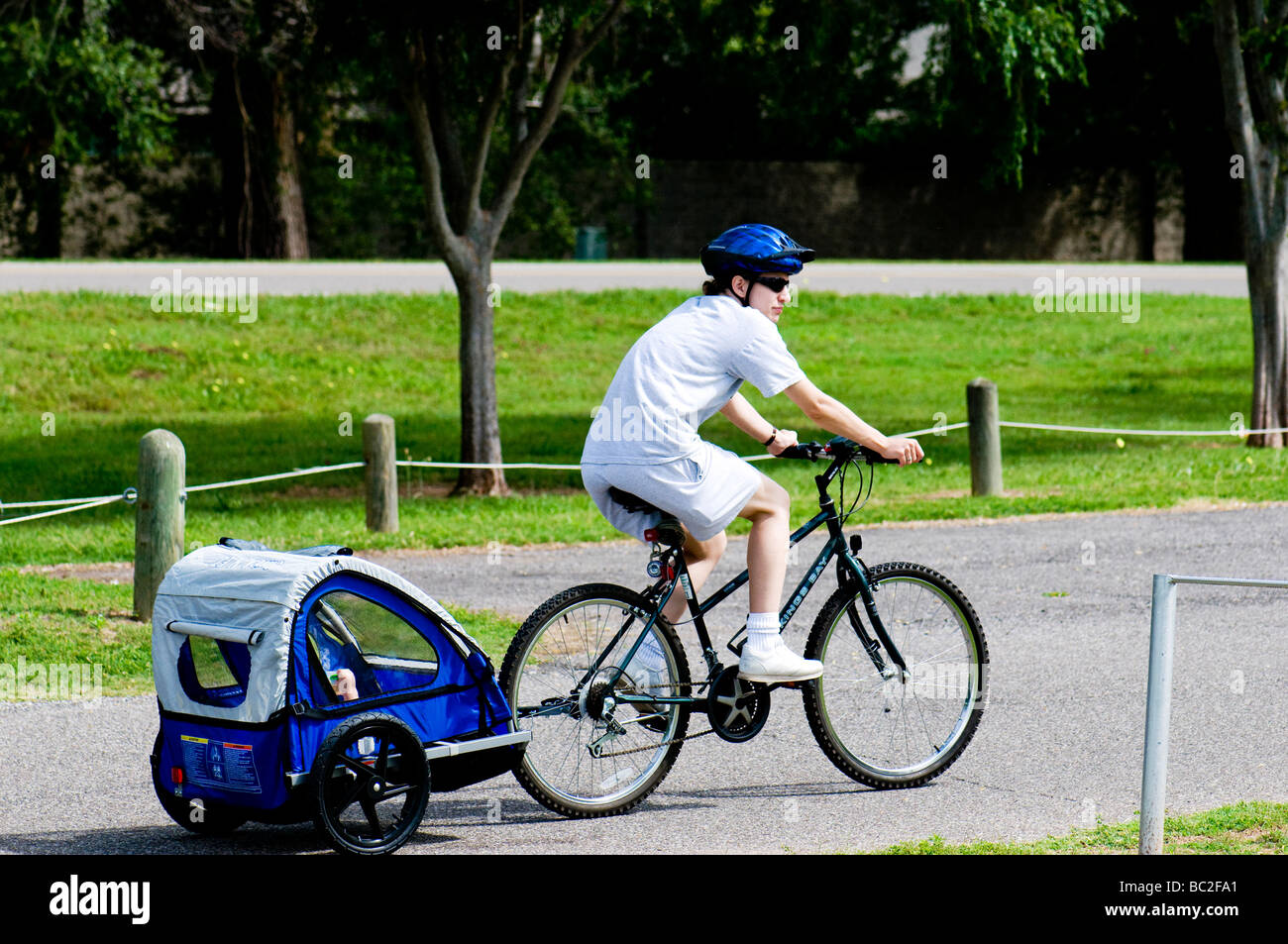 A young mother tows her child in a bicycle trailer in the USA. Stock Photo