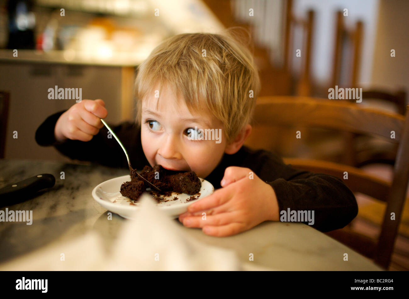 Young boy eating chocolate cake in a restaurant Stock Photo