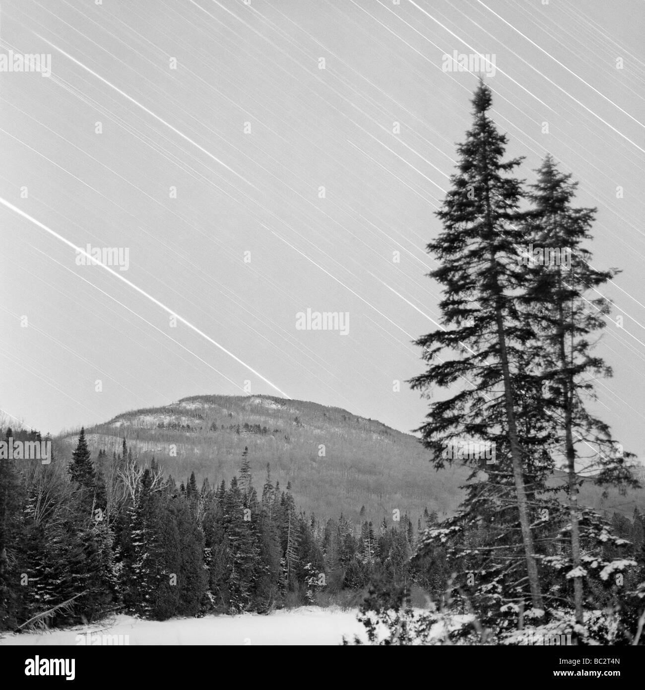 Winter landscape at night with star tracks over the sky Stock Photo
