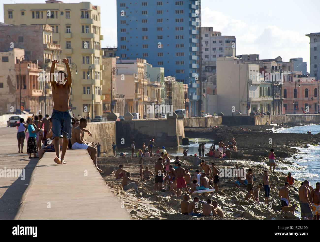 Cubans enjoying the sun and sea off the rocks alongside the Malecon, Havana, Cuba Stock Photo