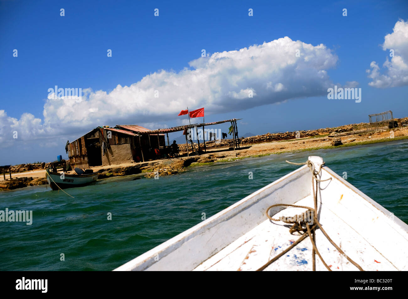 Fishing boat approaches shack on Cubagua Island, Venezuela. Stock Photo