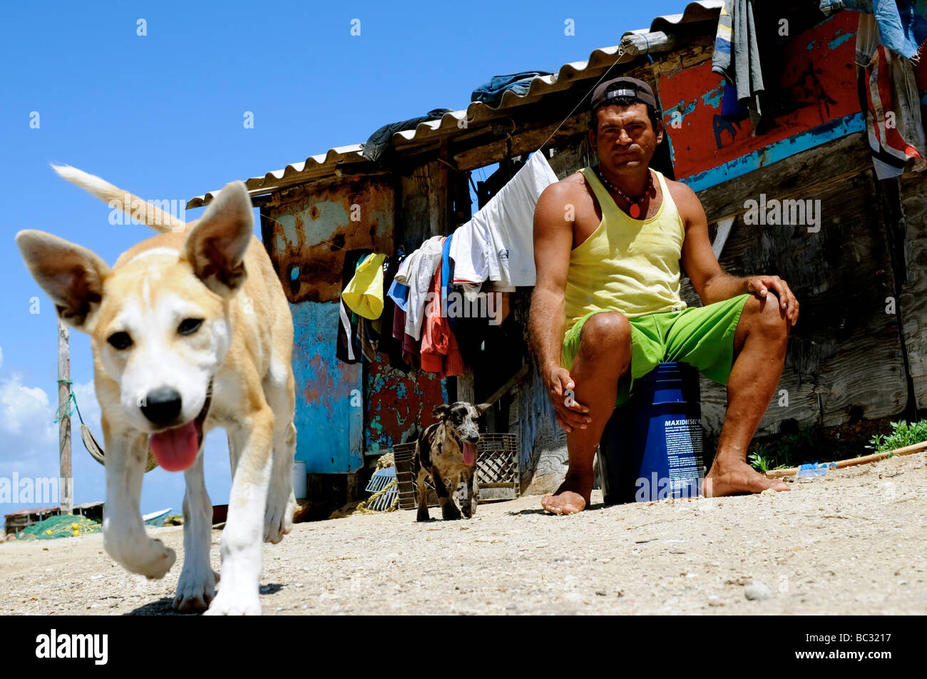 Fisherman sits with dog at home on Cubagua Island, Venezuela Stock Photo