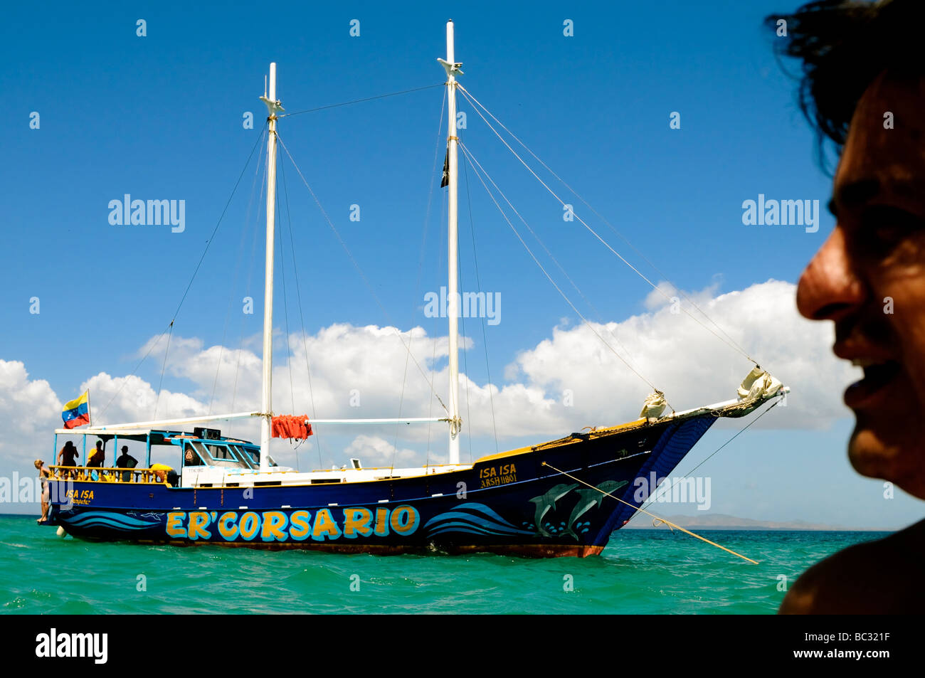 Tourist is disproportionately sized against touristy sail boat on the Caribbean Island of Cubagua in Venezuela. Stock Photo