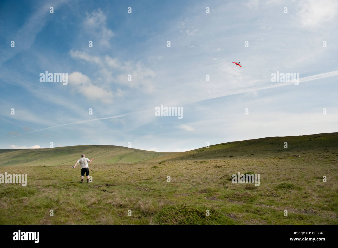A middle aged man flying a kite on the Preseli Hills north pembrokeshire Wales on a summer afternoon Stock Photo