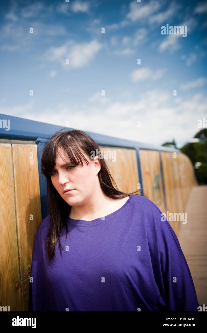 A Sad depressed young overweight woman girl person 18 to 21 years old standing on walkway bridge Stock Photo