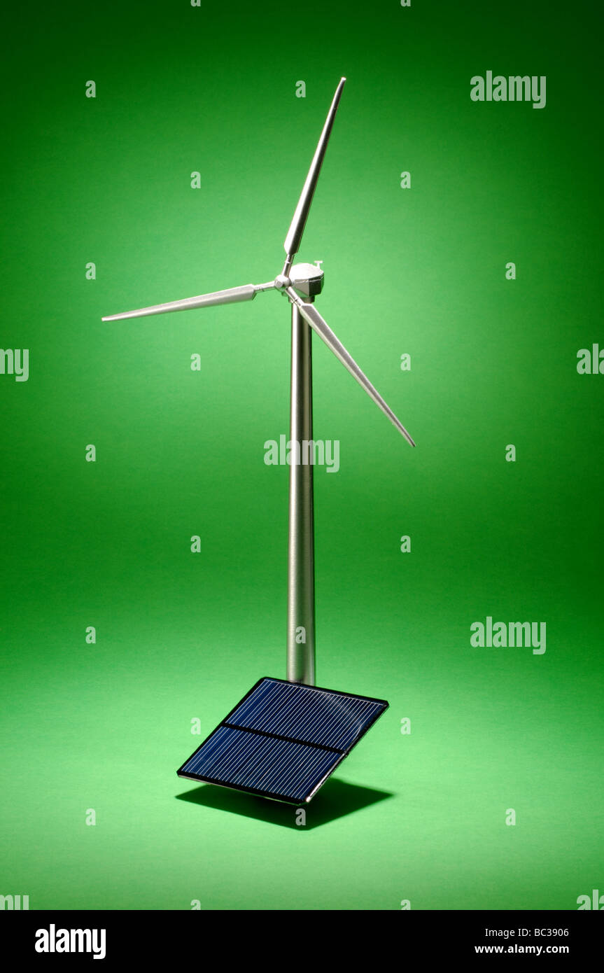 A small metal wind turbine on a green background with a small solar panel Stock Photo