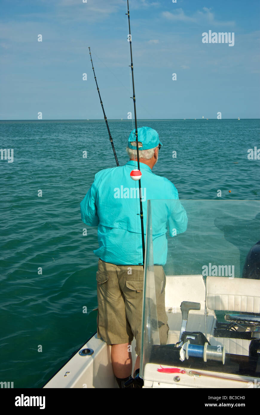 Male angler reeling in live bait suspended below small float tarpon