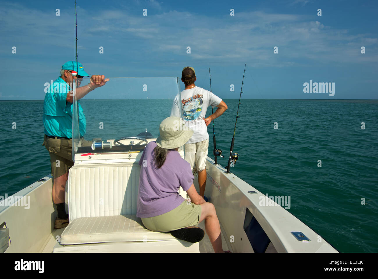 Male and female anglers with fishing guide waiting for tarpon fish to strike live baits suspended below small floats Stock Photo