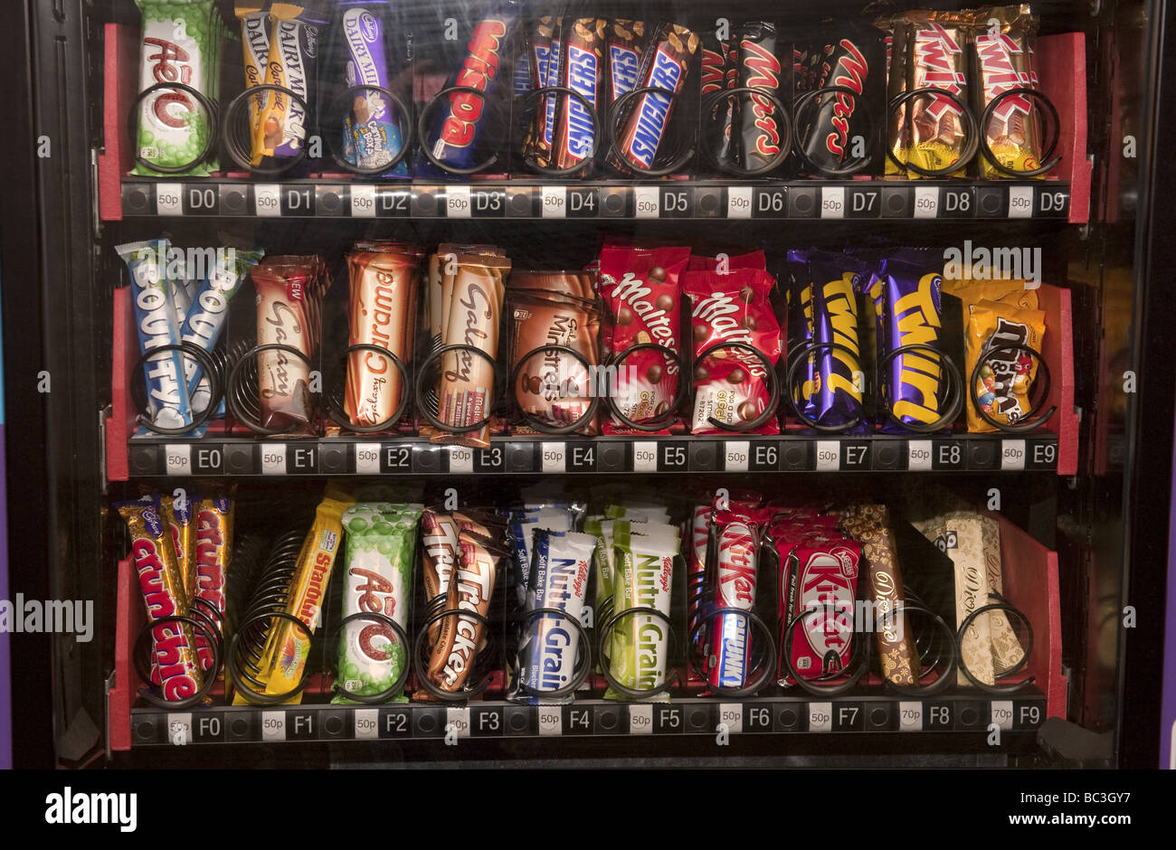 Close up of chocolate confectionary bars lined-up side by side in a recently restocked vending machine Stock Photo