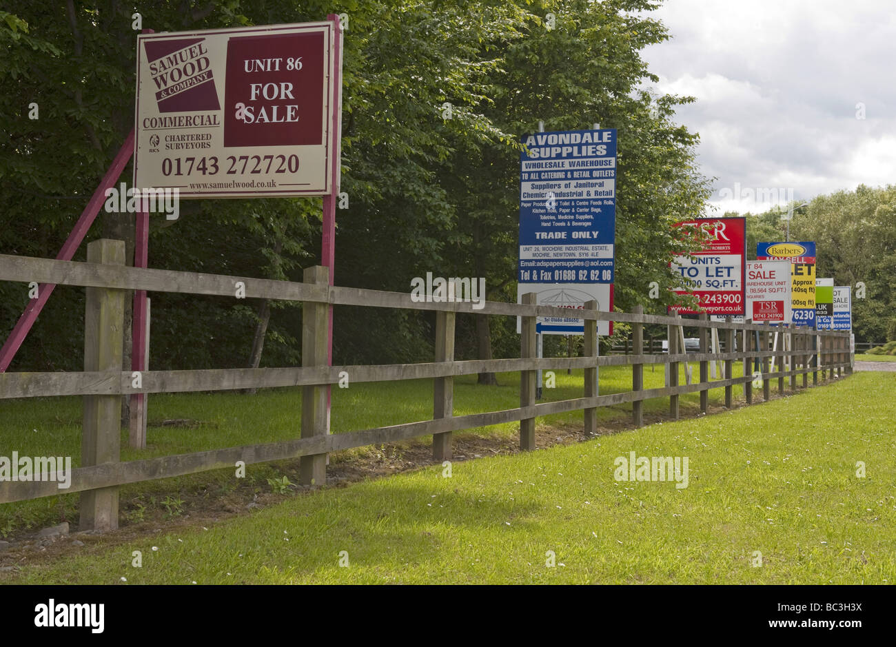 Multiple 'For Sale' and 'To Let' signs lining the roadside at an industrial estate site during economic recession times Stock Photo