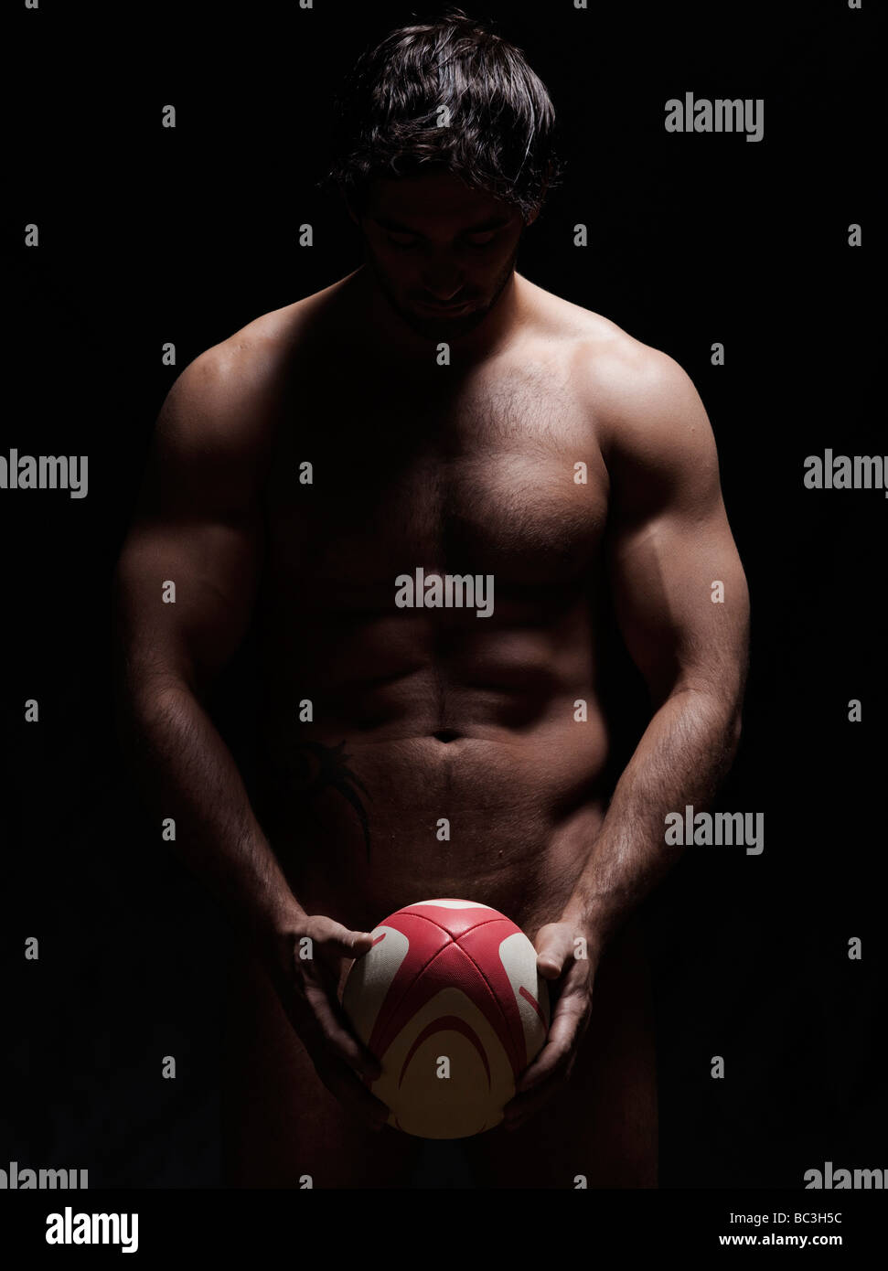 one caucasian sexy naked man portrait holding rugby ball on studio black  background Stock Photo - Alamy