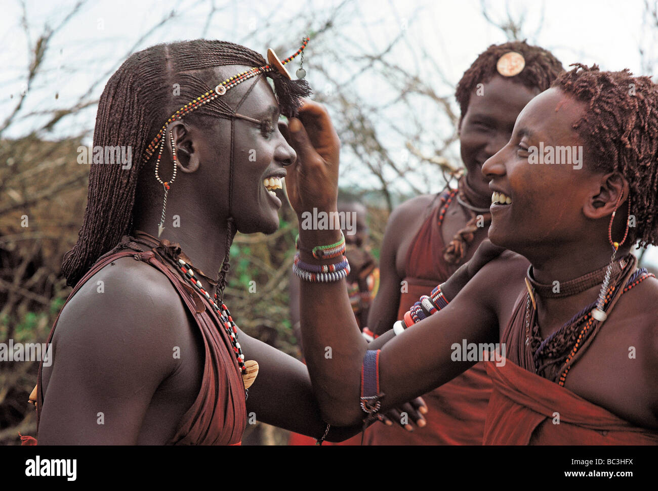 Portrait three Maasai warriors or MORAN adjusting each others hairstyle
