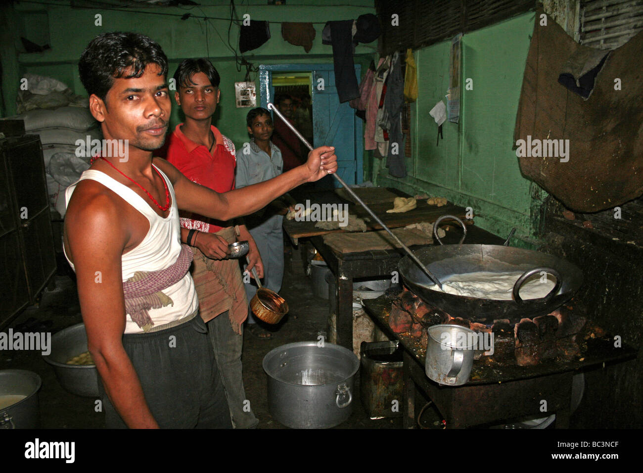 Young Assam Man Stirring Boiling Milk In the Kitchen Of A Chai Shop, India Stock Photo