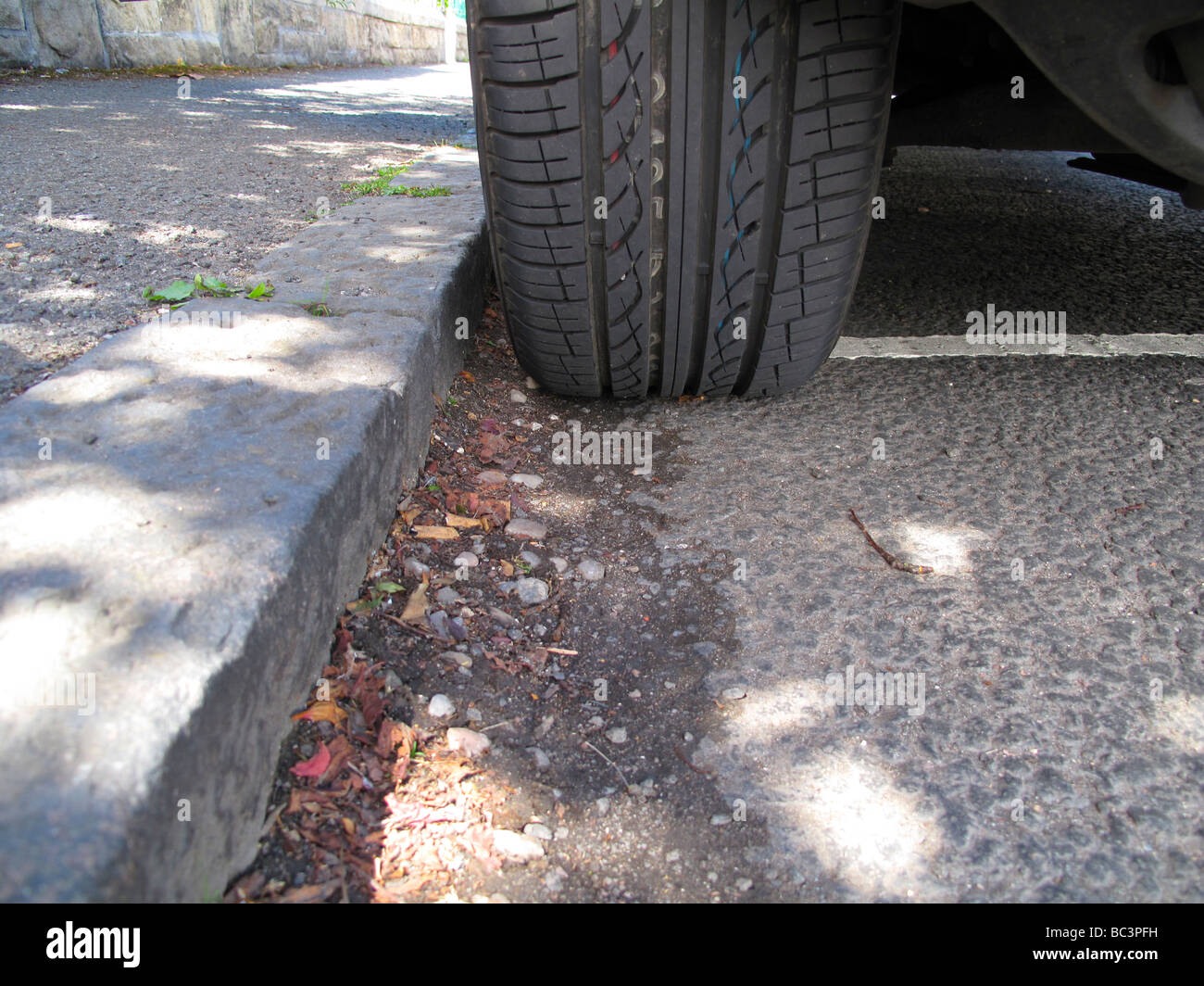 Parked car tyre at kerb Stock Photo