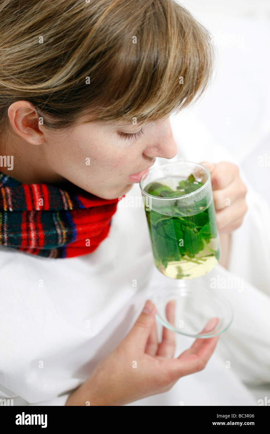 Woman in bed has a cold a sore throat Drinks a hot peppermint tea made