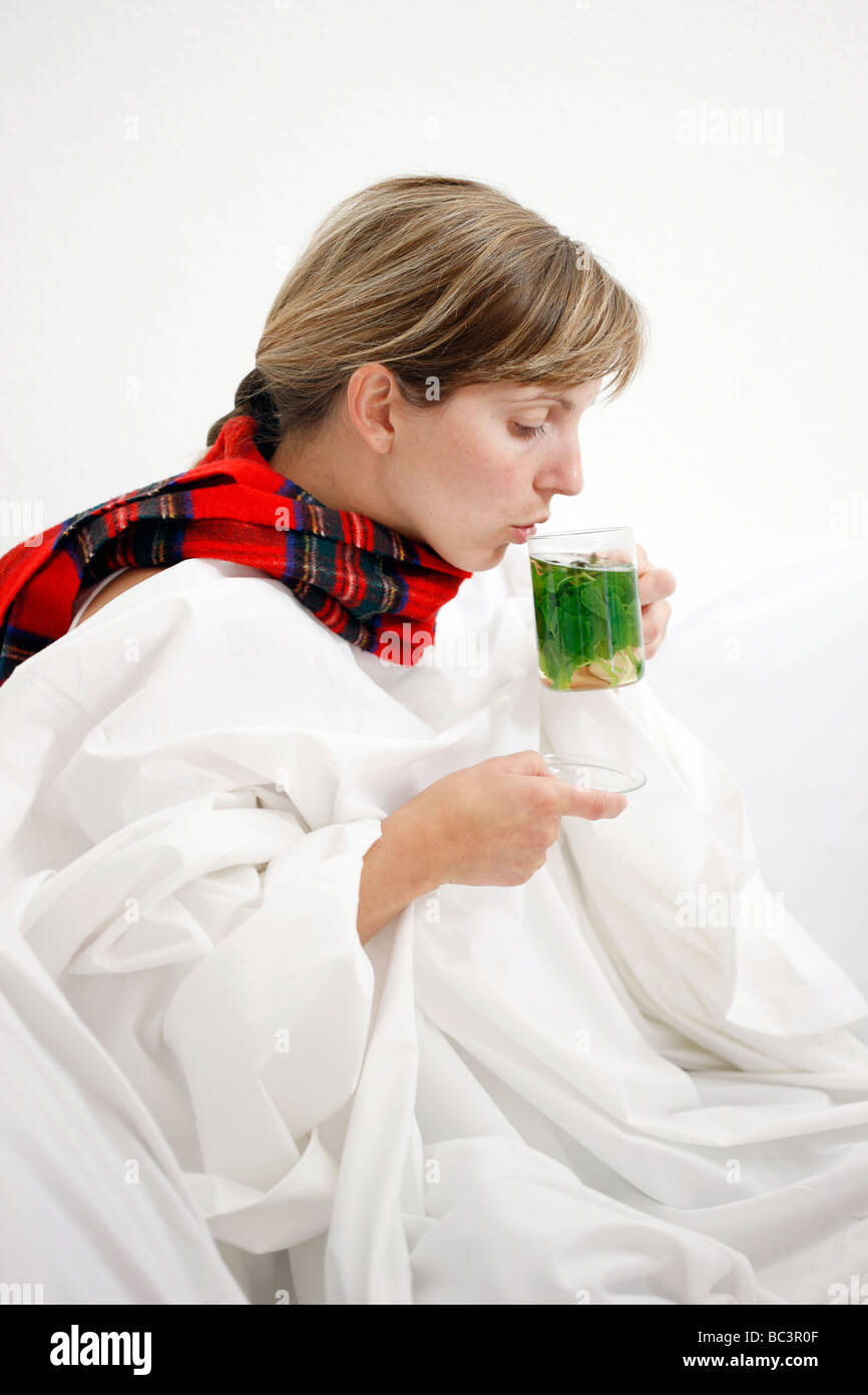 Woman in bed has a cold a sore throat Drinks a hot peppermint tea made