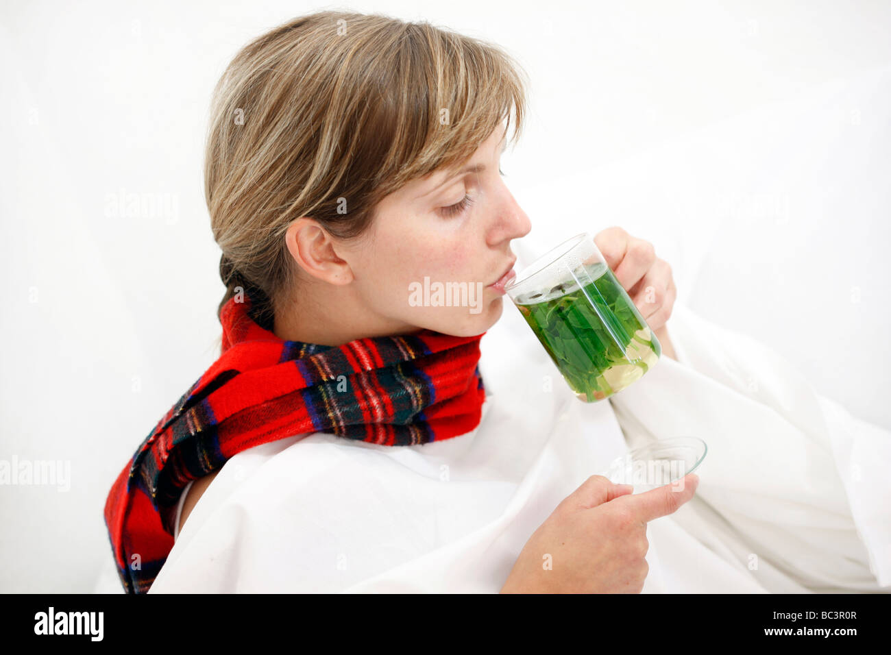 Woman in bed has a cold a sore throat Drinks a hot peppermint tea made