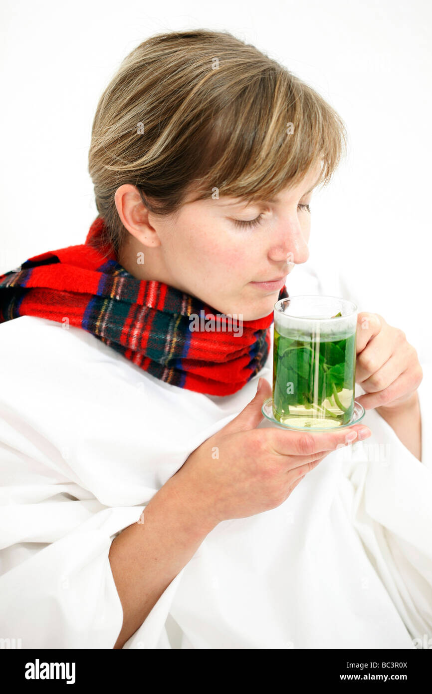 Woman in bed has a cold a sore throat Drinks a hot peppermint tea made