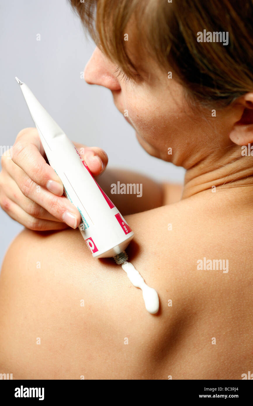 Woman is covering herself with ointment against pain Stock Photo