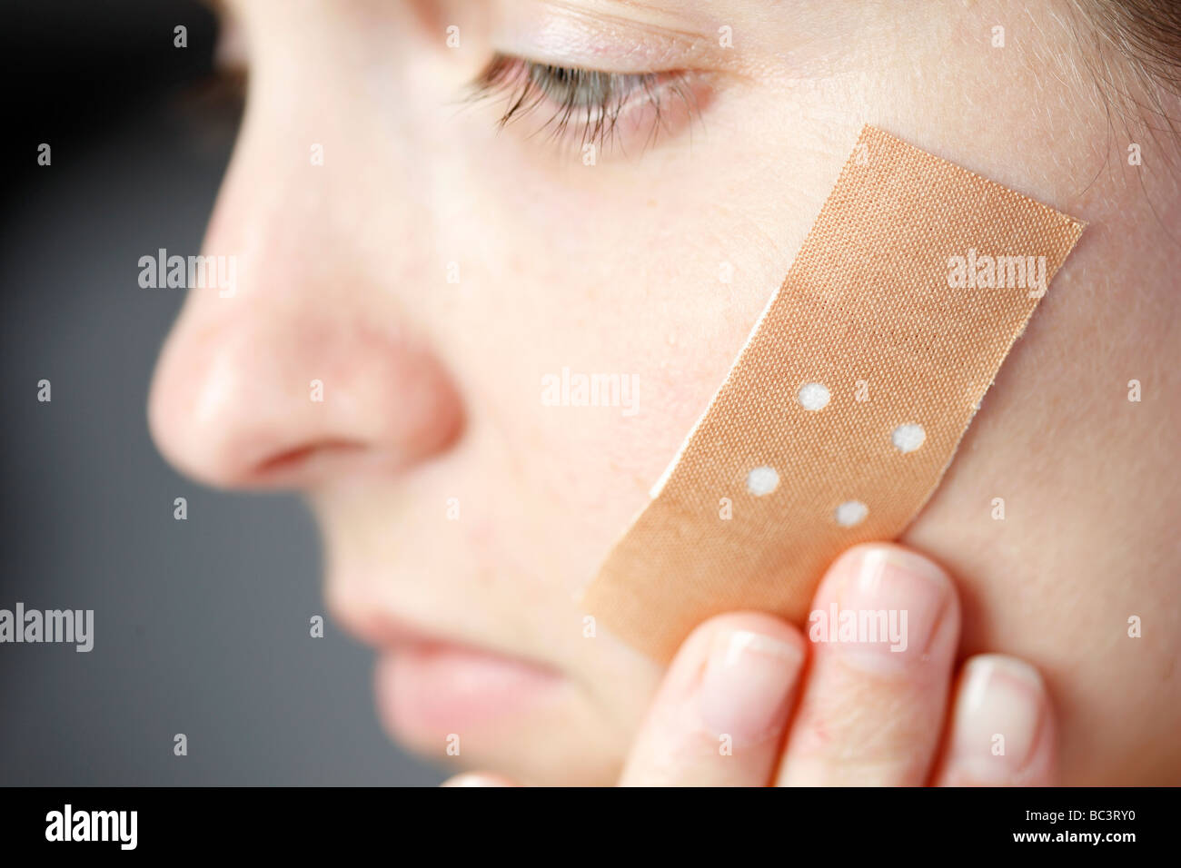 Woman has a plaster on her face Stock Photo