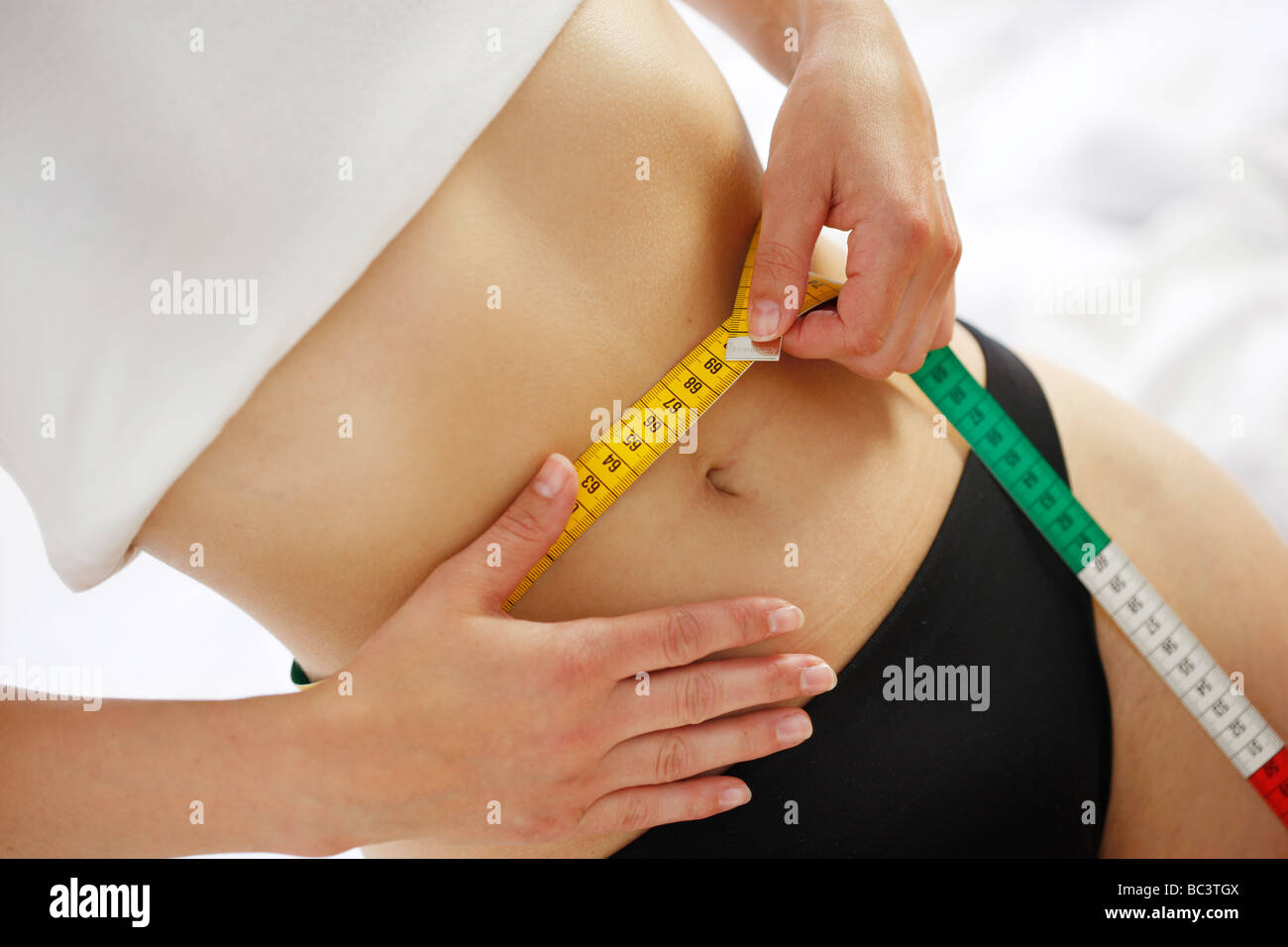 Woman is measuring her waist with a measuring tape Stock Photo